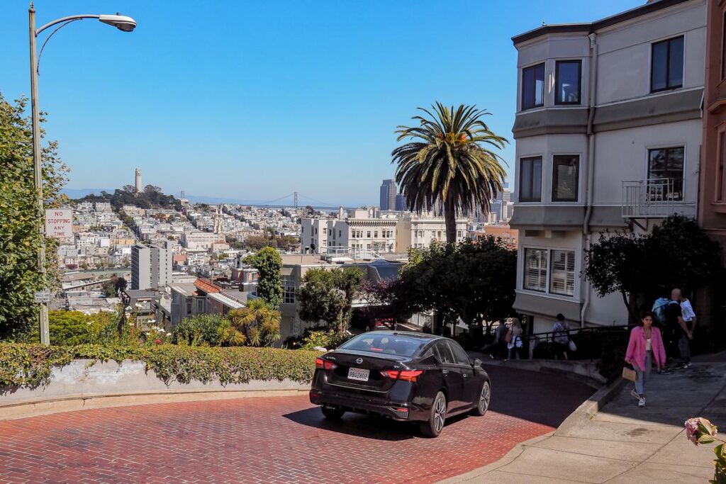 Scenic view of Lombard Street, Coit Tower, and San Francisco urban landscape on a sunny day.