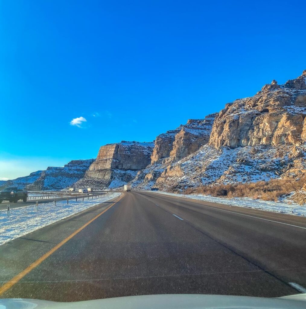 Scenic winter road trip through Wyoming's rugged landscapes, showcasing snowy cliffs and blue skies
