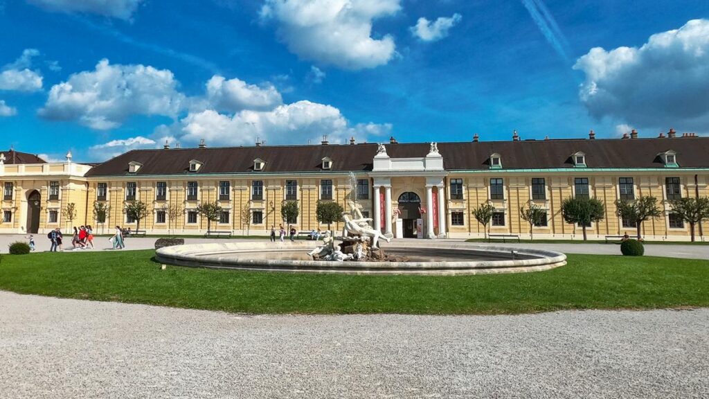Schonbrunn Palace with ornate fountain and statues, sunny day in Vienna