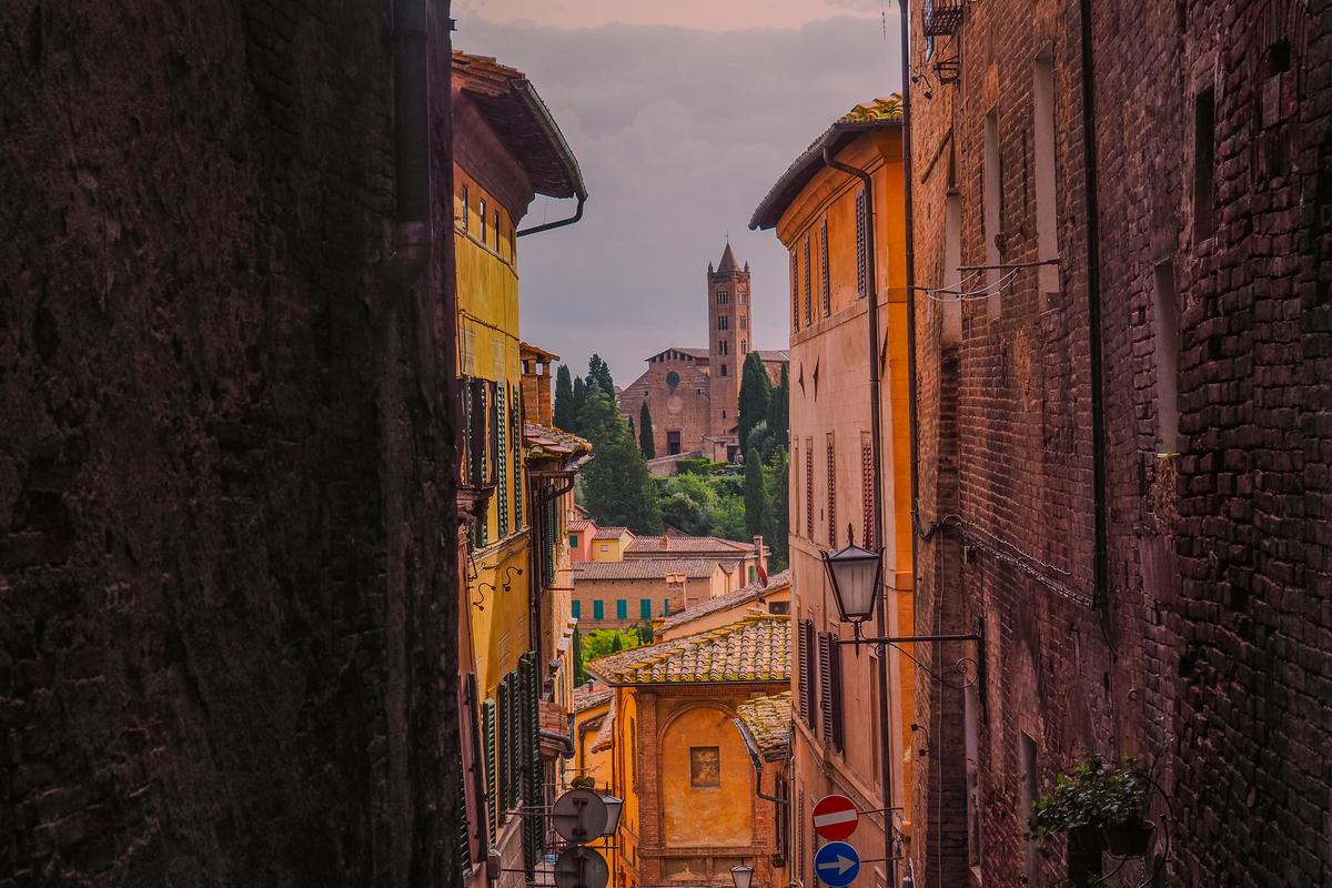 Historic alley in Siena with Tuscan architecture and distant tower