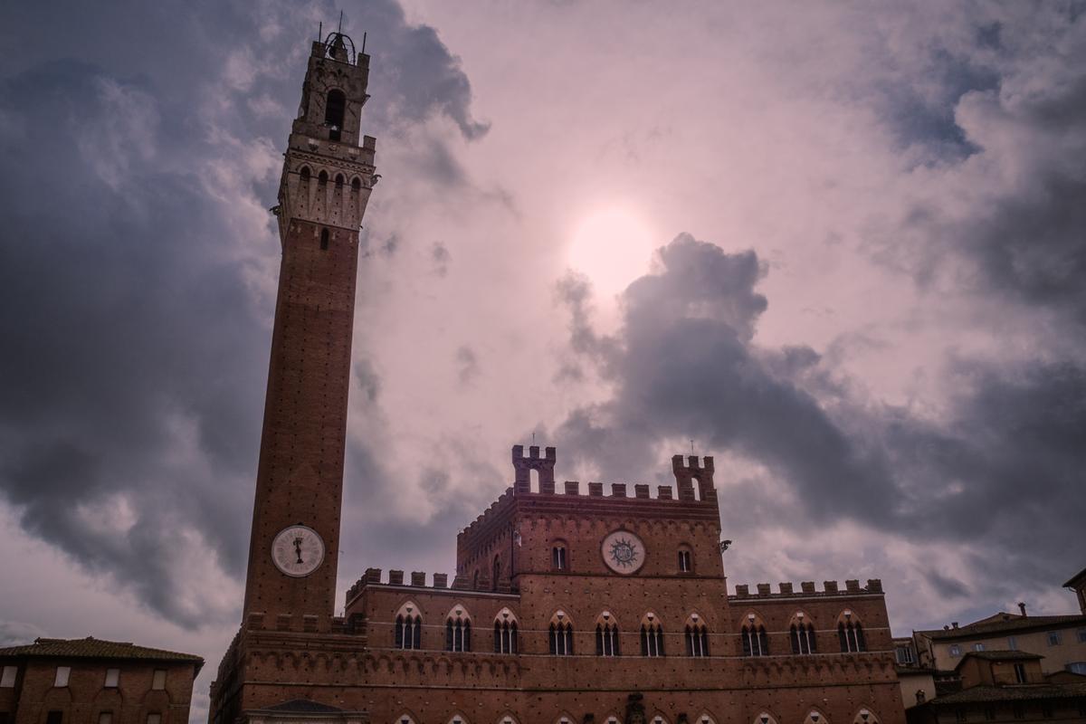 Historic Torre del Mangia silhouette in Siena, Italy under a dramatic sky