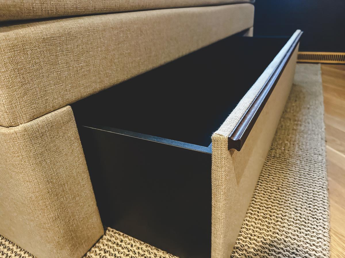 Scandinavian-style sofa with slide-out storage on natural fiber rug. Villa Copenhagen.