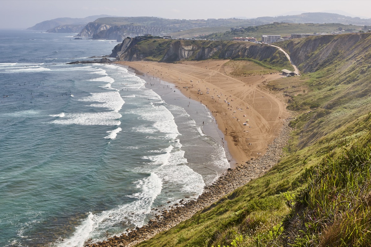 Aerial view of La Salvaje Beach Barinatxe, Sopelana, Basque Country, Spain with surfers and cliffs.