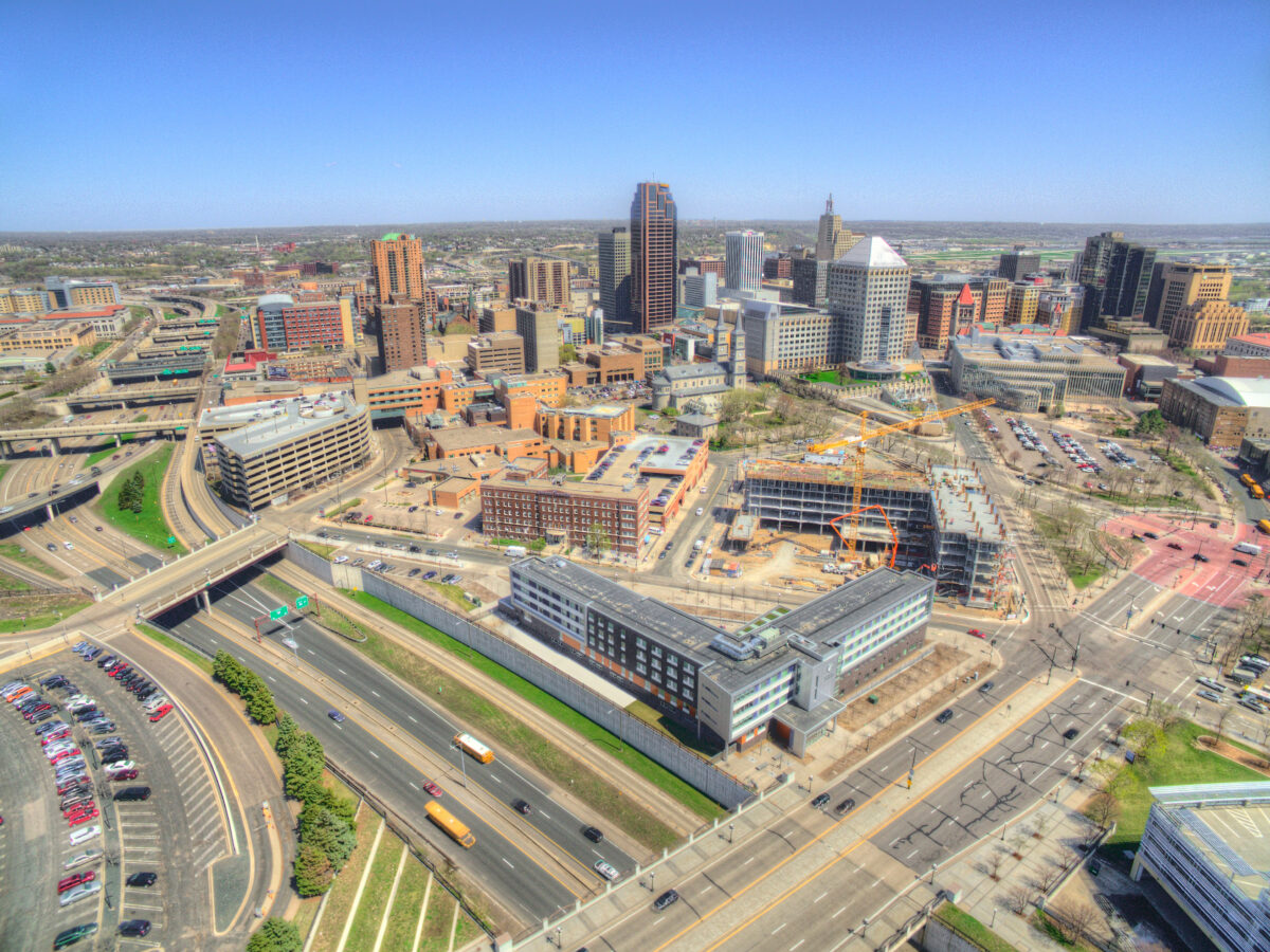 Aerial drone view of St. Paul, Minnesota: downtown skyline, State Capitol, highways, cranes and spring greenery.