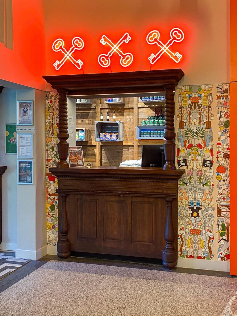 Stylish front desk check-in area at Generator Amsterdam hostel with neon sign and colorful wall art