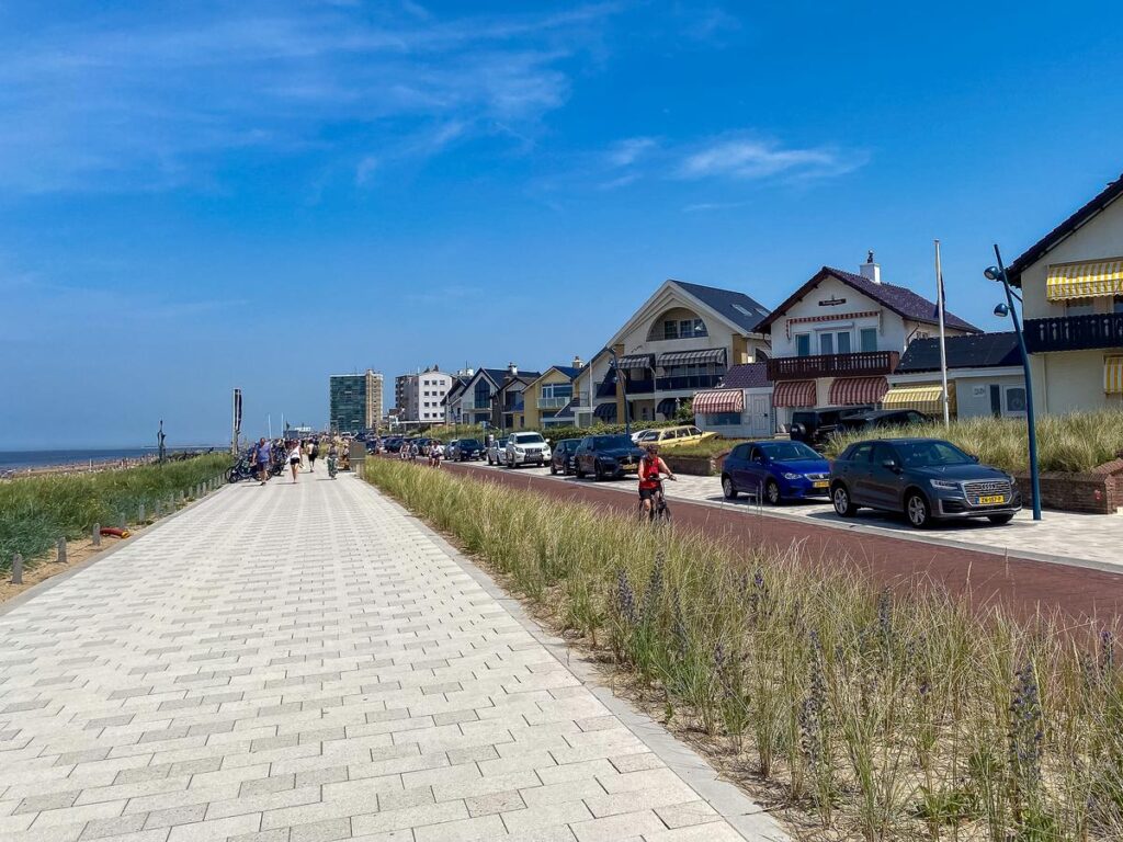Sunny Zandvoort Beach Boulevard, vibrant coastal scene with beachgoers, cyclists, and charming architecture.