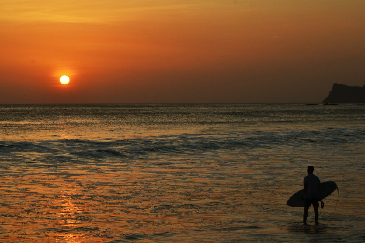 Surfer Walking into Ocean at Sunset in Nicaragua