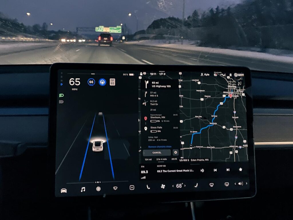 Tesla Model 3 dashboard with navigation map and autopilot function on night drive near Minneapolis.