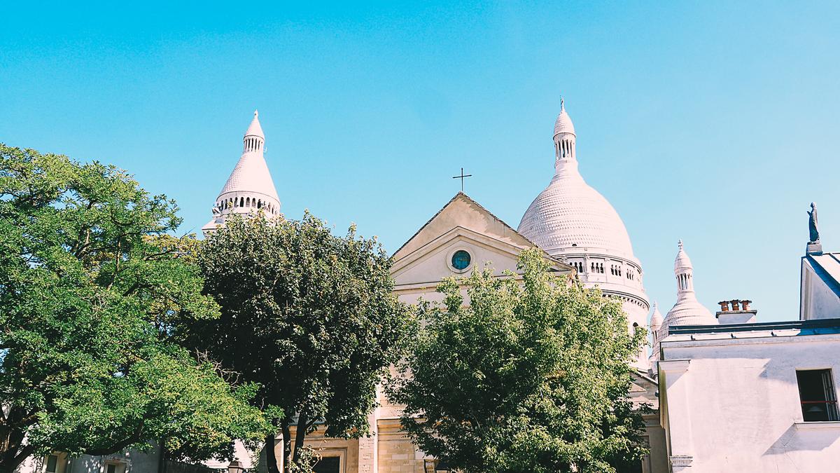The historic Paroisse Saint-Pierre de Montmartre church with the Sacré-Cœur Basilica in the background.