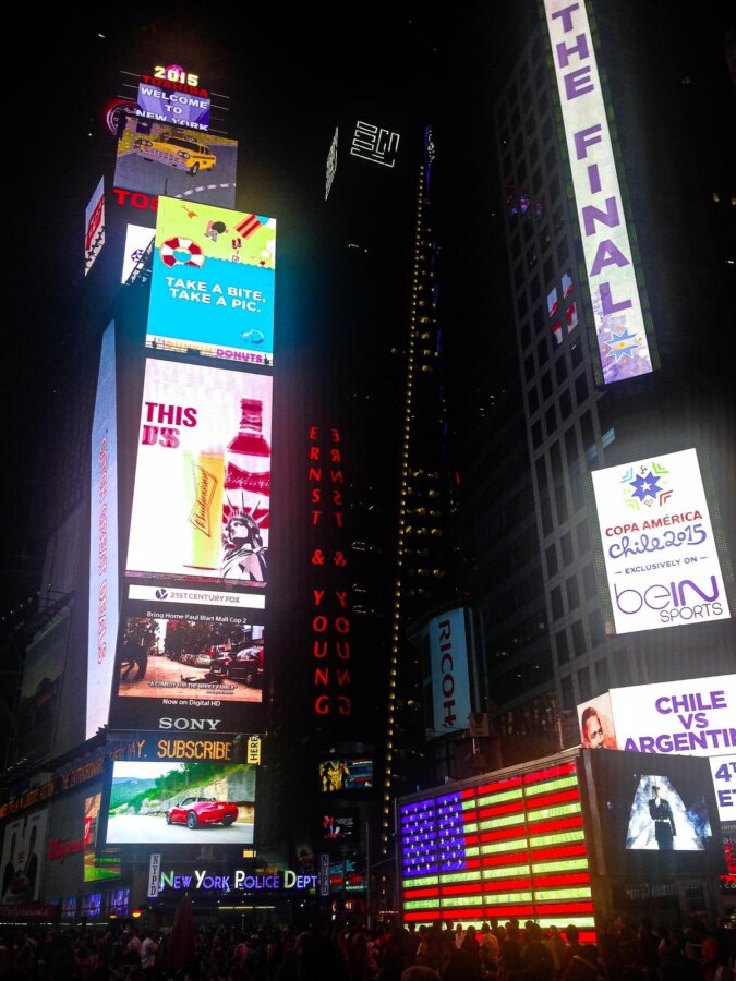 Times Square NYC at night with bright billboards and lively crowd
