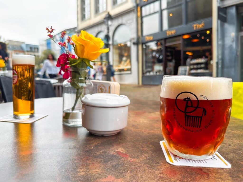 Traditional German beer experience at an outdoor café in Aachen with local brewery's logo Maschinenbau