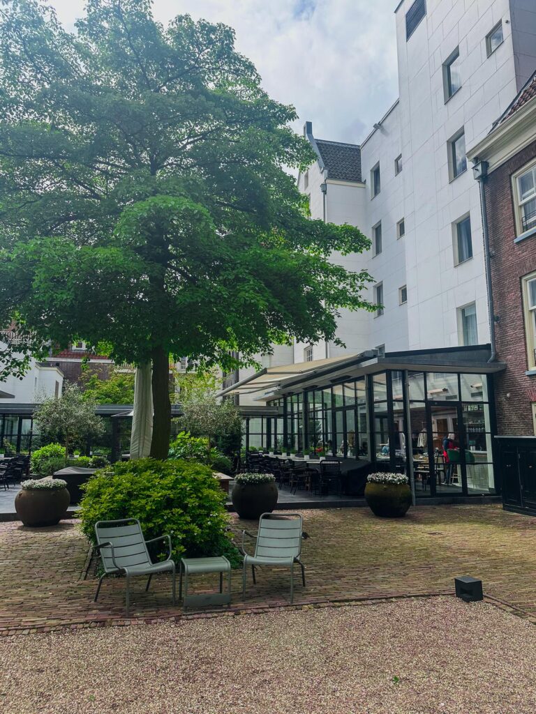 Tranquil courtyard oasis at Pulitzer Hotel, Amsterdam with elegant outdoor seating and greenery.