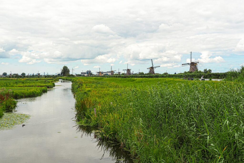 Dutch windmills at Kinderdijk surrounded by lush greenery and waterways under a cloudy sky.