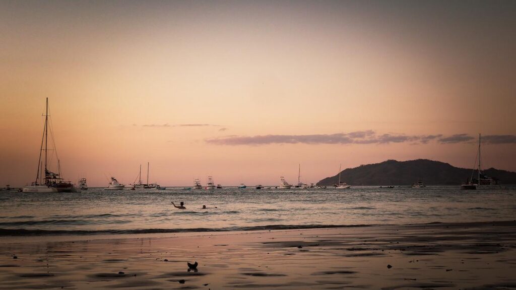 Tranquil sunset at Playa Tamarindo, Costa Rica: serene beachfront with moored sailboats and leisure activities