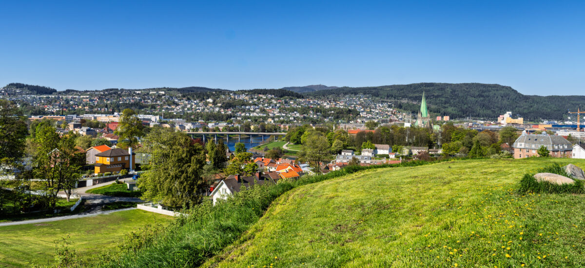 Trondheim, Norway: scenic riverside town with colorful houses, green hills, and spring waterfront.
