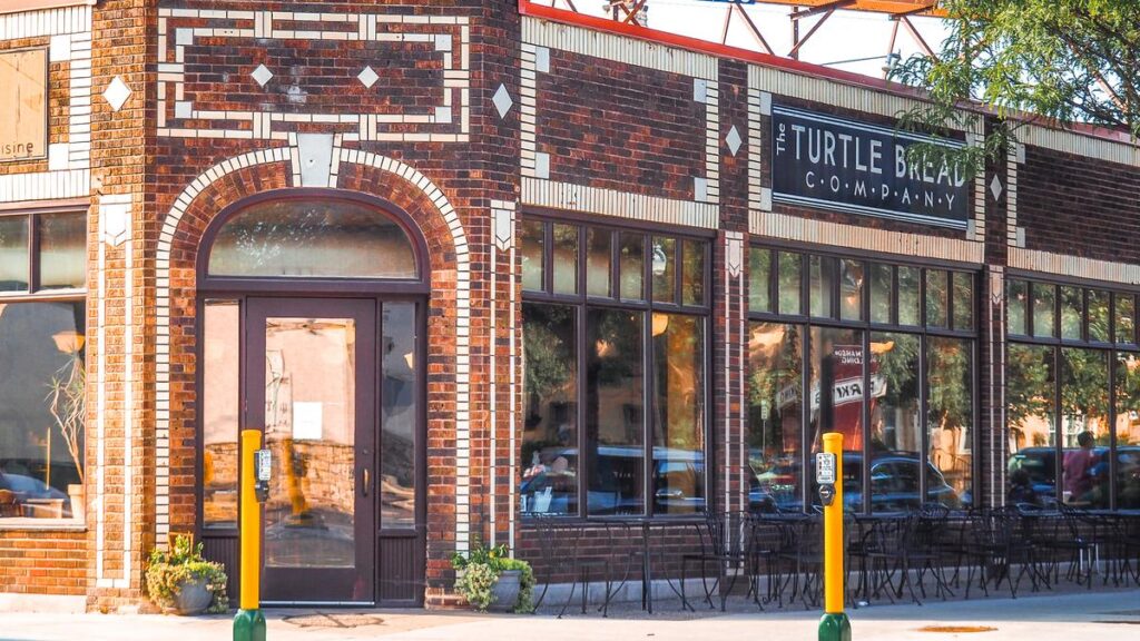 The Turtle Bread Company storefront in Minneapolis with clear windows and outdoor seating under bright sunlight.