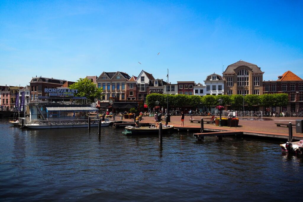 Vibrant canal scene in Leiden, Netherlands with traditional Dutch architecture and boat tour dock.