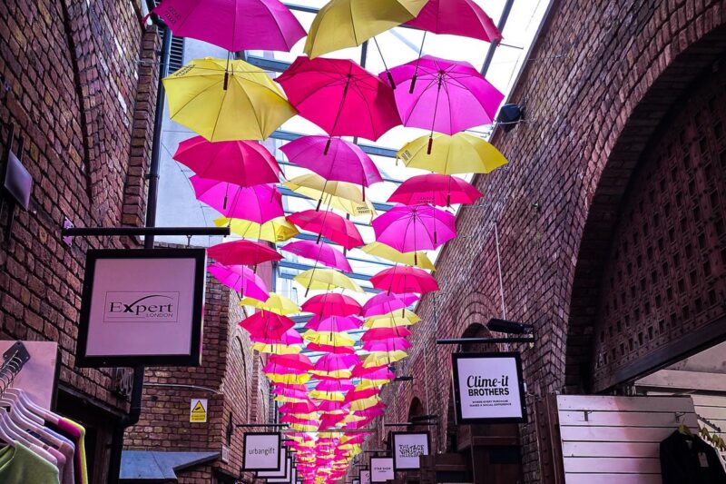 Vibrant umbrella canopy at Camden Market, London - A unique charm under pink and yellow umbrellas. Dynamic atmosphere of London's iconic market.
