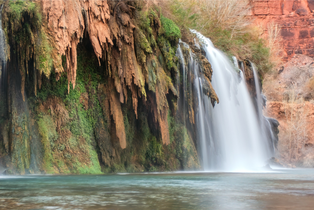 Fifty Foot Falls Havasupai  over mineral-rich cliff into a tranquil pool; mossy rock face and canyon scenery.