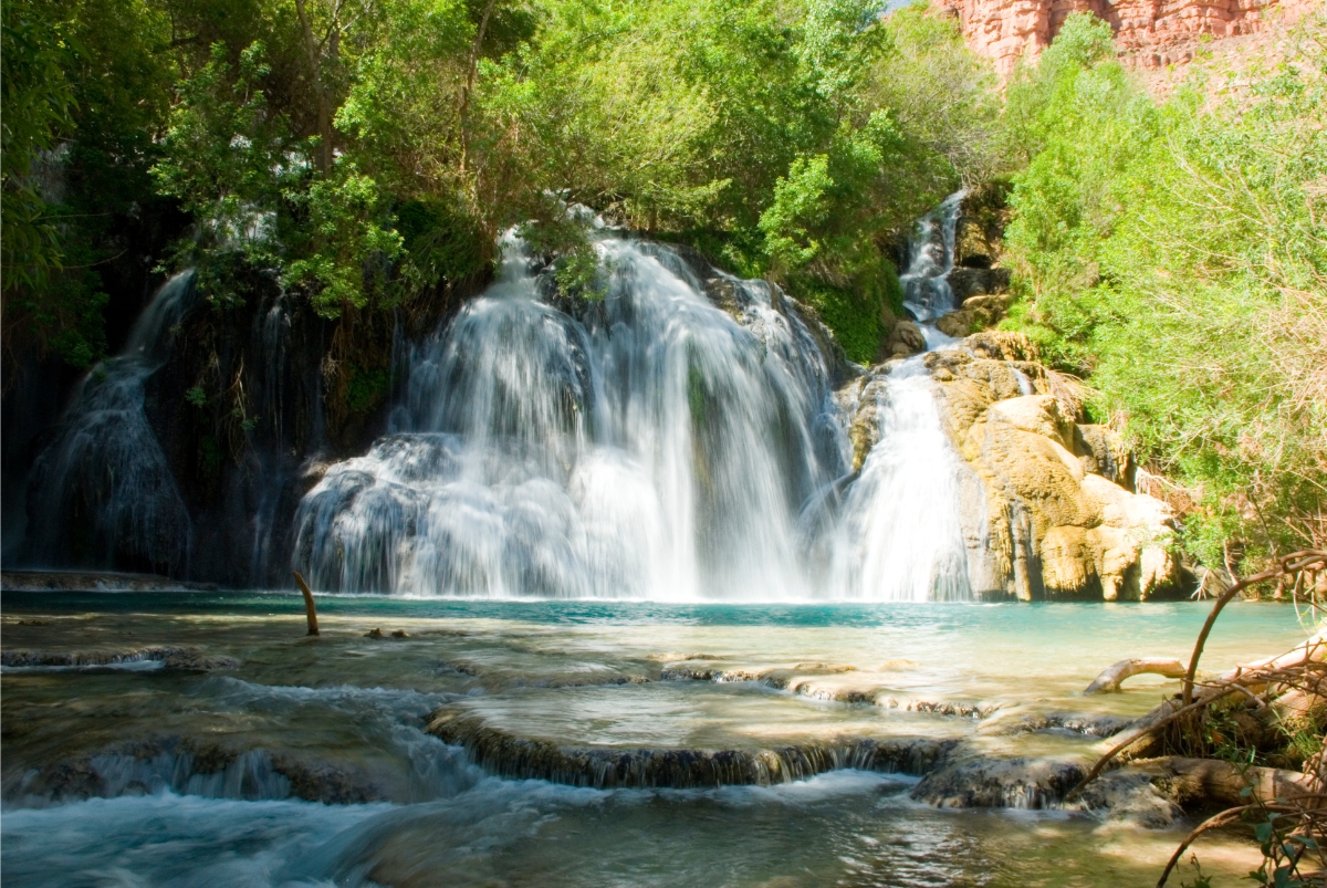 Navajo Falls Waterfall  Turquoise pool beneath a multi-tiered waterfall with travertine terraces, lush forest, and sunlit rock cliffs.