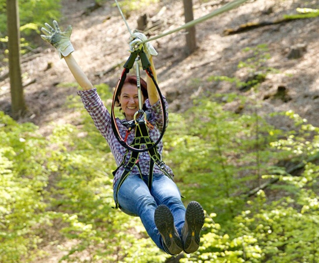 Woman enjoying a forest zip line in Germany adventure.