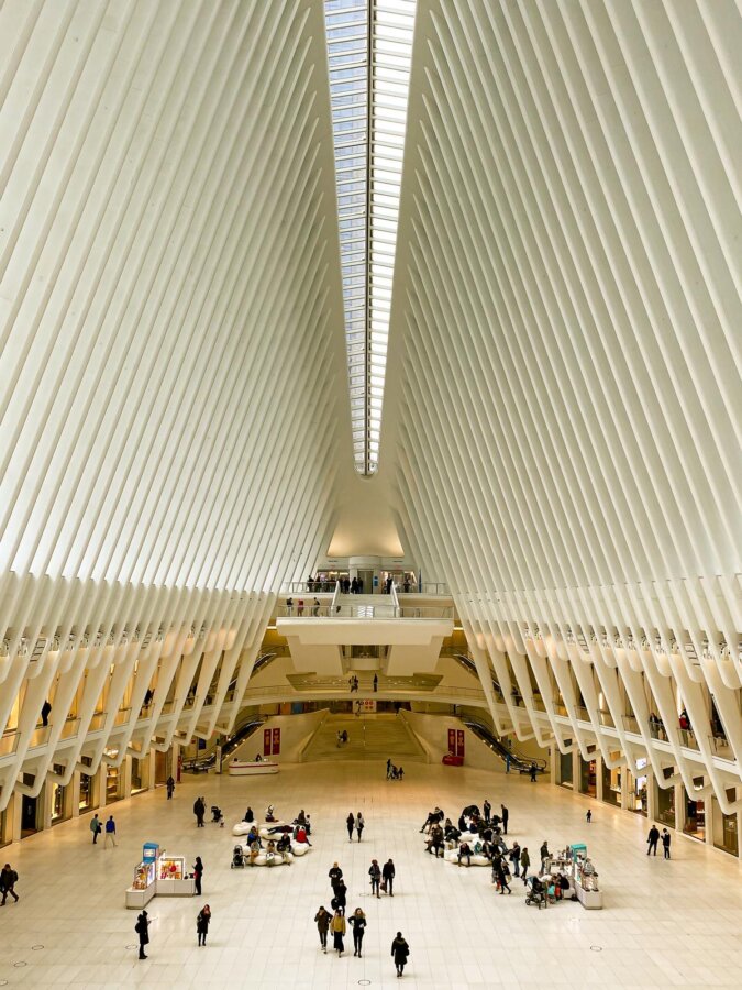 Oculus interior at World Trade Center Station, NYC with commuters and shops.